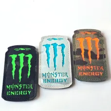 Three Monster Energy laser cut Cordura Velcro patches: black with neon green, white with turquoise, and camouflage with orange details.