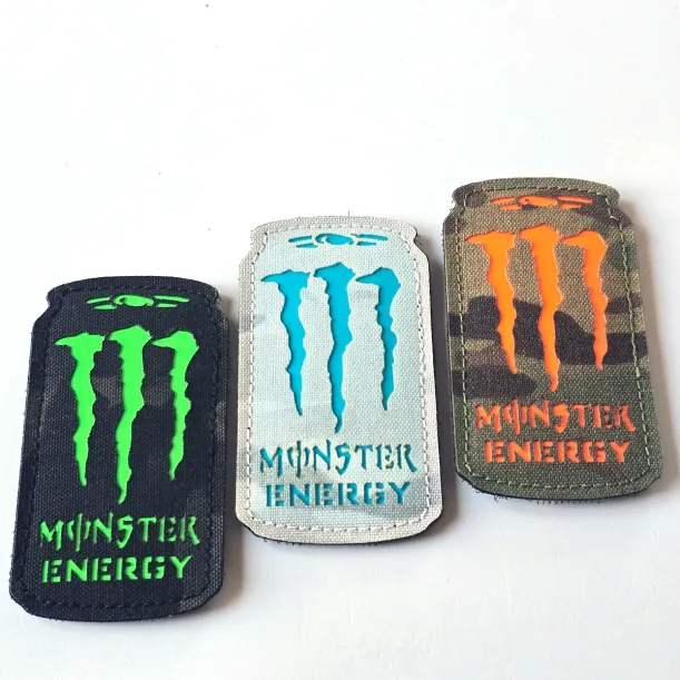Three Monster Energy laser cut Cordura Velcro patches: black with neon green, white with turquoise, and camouflage with orange details.